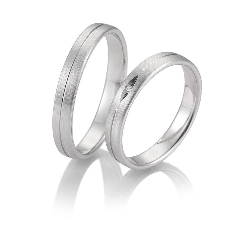 Eksklusive Breuning vielsesringe i 9 eller 14 karat hvidguld med silkemat overflade, graveret streg og 0,01 ct diamant i damering.